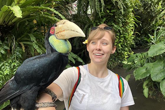 Photo of a 2024欧洲杯官方投注 student in a jungle with a large exotic bird perched on her arm