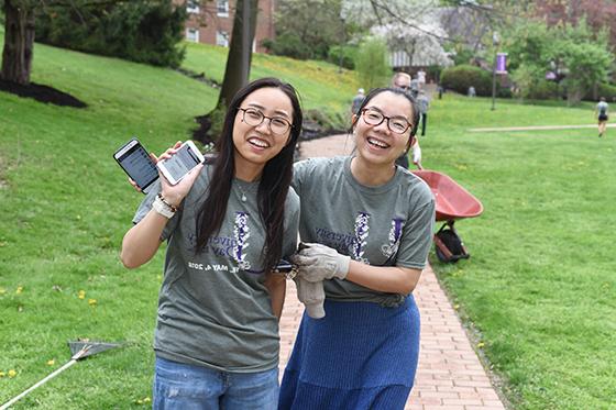 Photo of two international students on 2024欧洲杯官方投注's 欧洲杯官方投注网站, pausing while volunteering to plant flowers